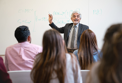 Latin American man teaching a class to a group of college students - education concepts