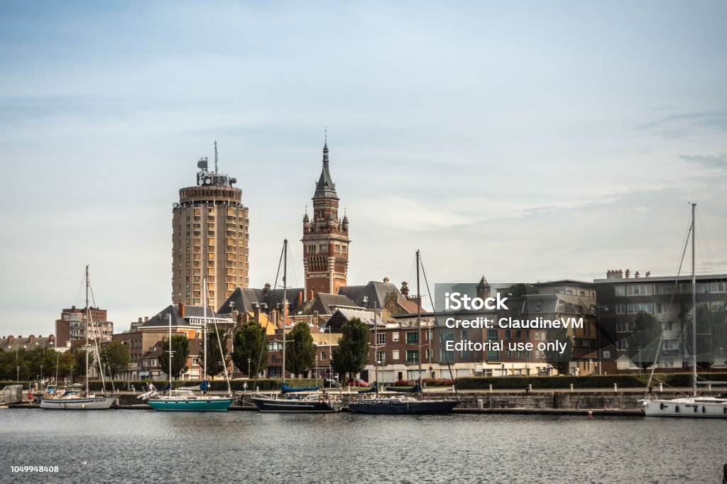 Old port with two towers of Dunkirk, France. Dunkerque, France - September 16, 2018: Old Port with sailing yachts and two towers: condominiums, Belfry of Dunkirk town hall under light blue sky. Red brick other buildings. Dunkirk - France Stock Photo