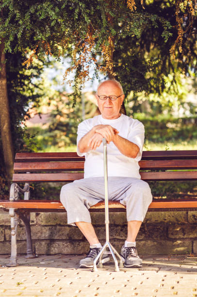 istock Sad pensioner man with his walking stick sitting on bench 1049956398