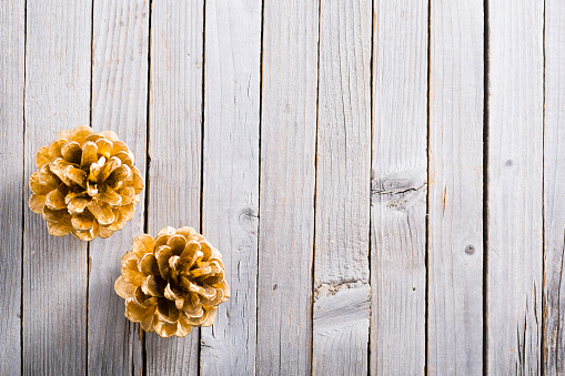golden pine cones Christmas decoration on old rustic wooden table background