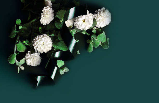 The concept of mourning. White flowers on a dark background and a candle. We remember, we grieve. Selective focus, place for text.