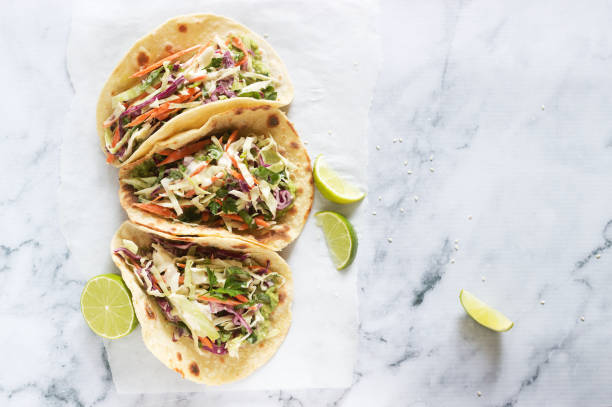 tacos mit guacamole und krautsalat serviert mit limettenscheiben auf hellem hintergrund. - guacamole avocado mexican culture food stock-fotos und bilder