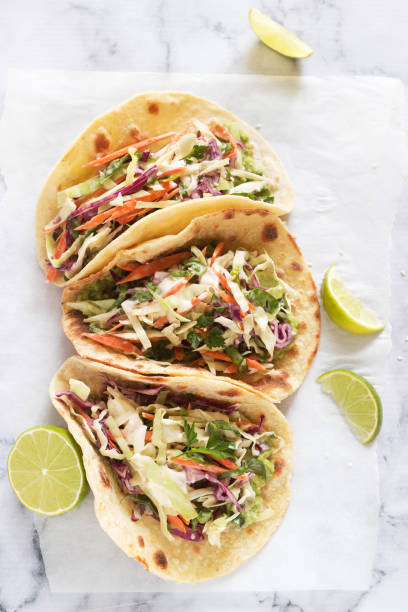 istock Tacos with guacamole and coleslaw served with lime slices on a light background. 1049979146