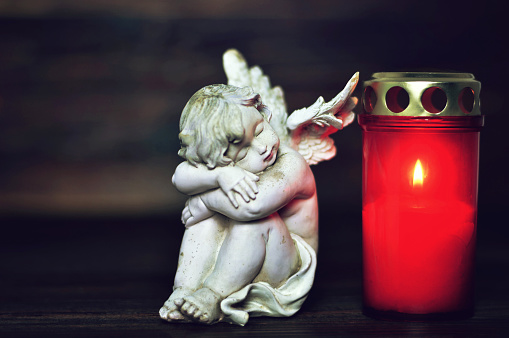 Sleeping angel and All Saints Day burning candle