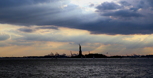 Statue of Liberty under clouds and sun rays