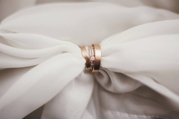 istock Marriage concept. Modern wedding golden rings with diamonds on soft fabric, creative image. Wedding rings on tulle in light. Space for text 1050006432