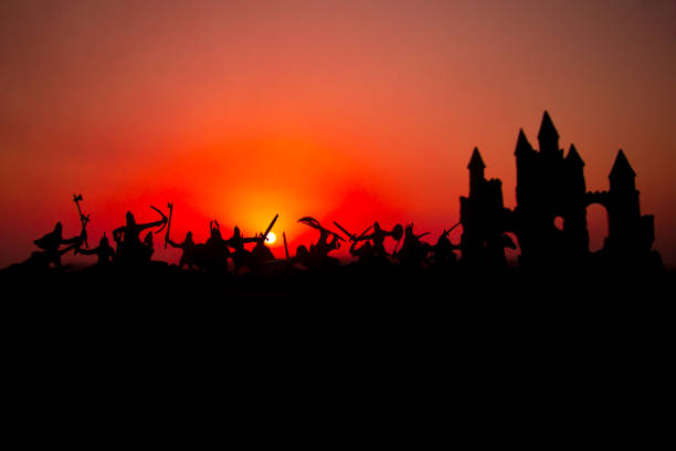 istock Medieval battle scene with cavalry and infantry. Silhouettes of figures as separate objects, fight between warriors on sunset foggy background. 1050006500