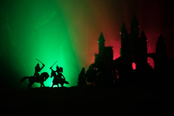 istock Silhouettes of figures as separate objects, fight between warriors on dark toned foggy background with old gothic castle 1050006596