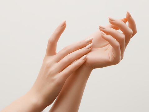 Closeup imagen de manos de mujer hermosa con luz rosa manicura en las uñas. Cuidado para manos, de la piel tratamiento de manicura y belleza. Elegantes y gráciles manos con dedos agraciados delgados photo