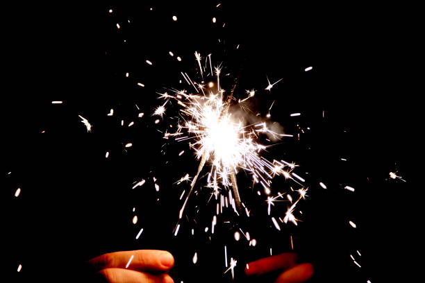 istock two Bengal fire in hands sparkles on black background 1050009300