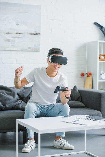 istock excited young man in virtual reality headset playing with joystick at home 1050012556