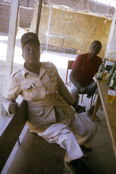 Congolese village policeman at the after-work beer Congo, Central Africa, 1974. Congolese village policeman at the after-work beer with villagers. bar drink establishment stock pictures, royalty-free photos & images
