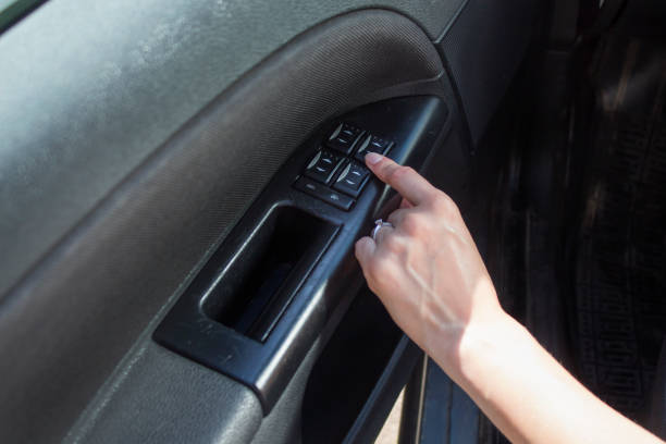 istock Woman's hand touches the window adjustment button in the car. 1050016062