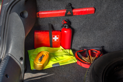 Interior de la cajuela del carro en el que hay un kit de primeros auxilios, extintor, triángulo de advertencia, chaleco reflectante, cuerda de remolque y cables de arranque photo