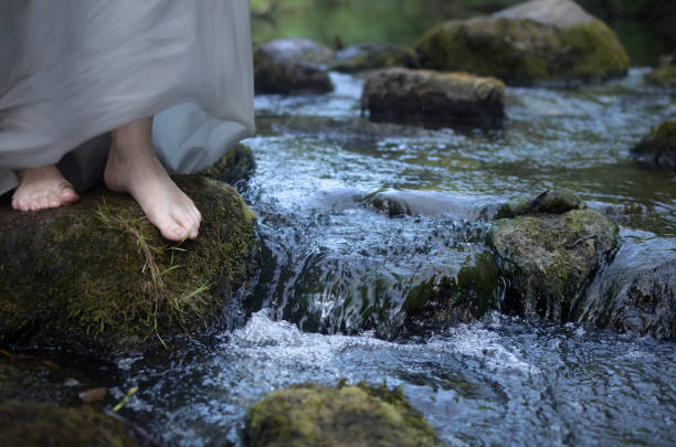barefoot women's feet on a stone among the fast-flowing river