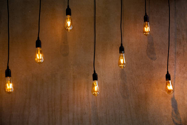 istock hanging lighted bulbs near a cement wall hanging from their black power wire 1050038084