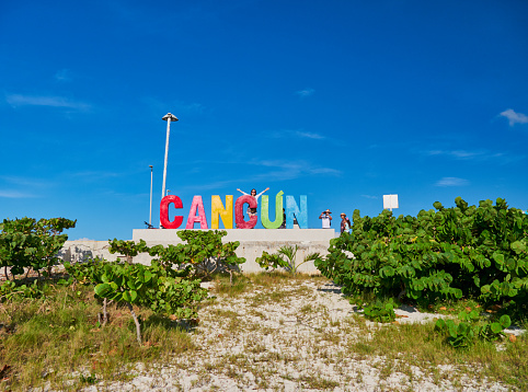 Girl lifts her arms up in front of Cancun sign, Playa Delfines, Mexico, in September 7 , 2018