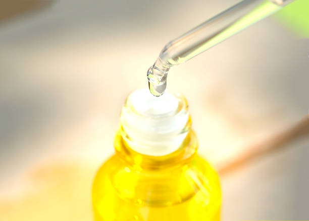 istock Dropping serum collagen moisturizer of face into clear yellow bottle soft light background. Protector skin Treatment facial essence oil, Vitamin C. Beauty and spa Concept. 1050072242