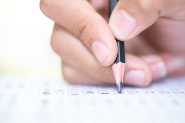 istock Pencil on hand to writing answer of test examination on answer paper 1050085890