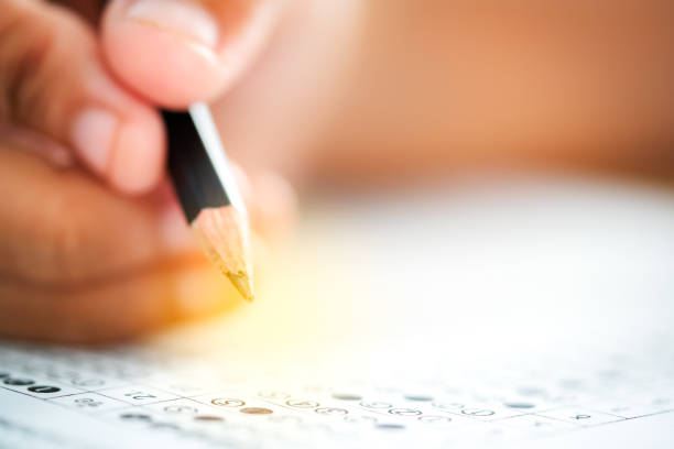 istock Pencil on hand to writing answer of test examination on answer paper 1050085932