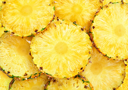 heap of ripe pineapple slice as textured background