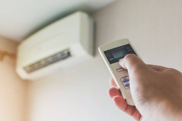 istock Concept save energy save world. Hand holding air condition remote and turning off 1050099004