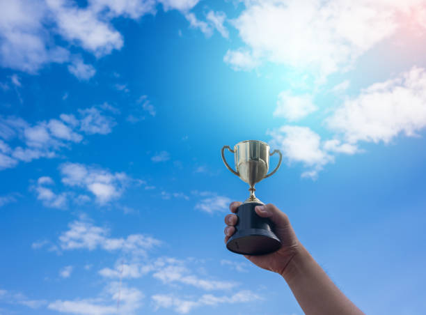 istock Man holding up a gold trophy cup,win concept. 1050109670