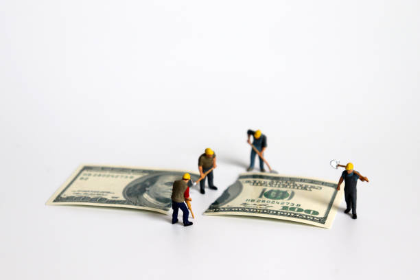 istock A hundred dollar bill torn in half with miniature worker. 1050116770