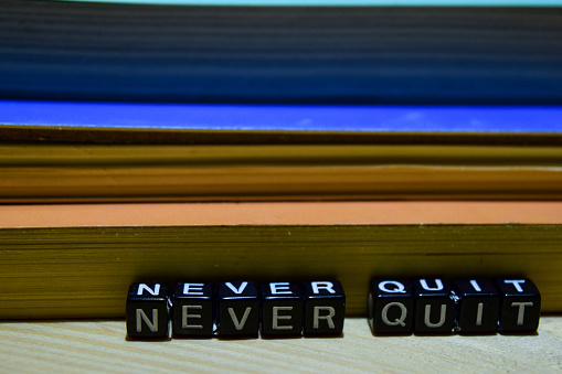 Never quit written on wooden blocks. Education and business concept on wooden background