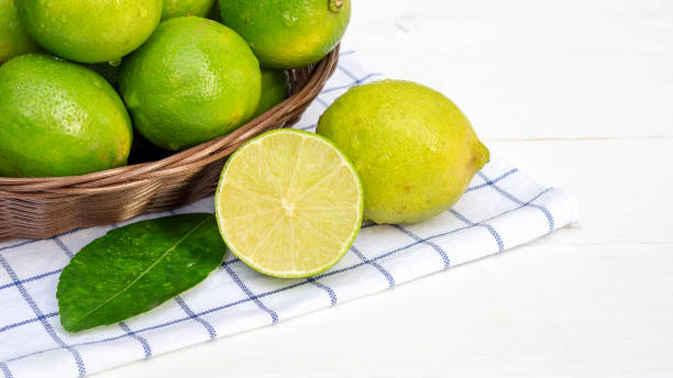 istock Green lime in a basket on a white wooden table. 1050127558