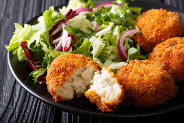 istock Delicious fish appetizer: cod cake in breading with fresh salad close-up. horizontal 1050140942