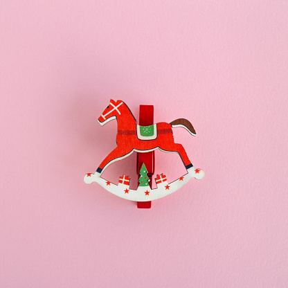 Red wooden Christmas and New Year decoration in the form of horse on a pink background, top view.