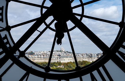 Paris, France - September 20, 2018: Paris, France - September 20, 2018: Paris cityscape through the giant glass clock at the Musee d'Orsay with view on the Tuileries Garden, Palais royal, Opera Garnier and Montmartre - Paris, France