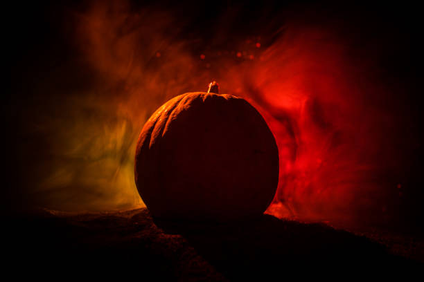 istock Halloween theme with pumpkin against smoky dark background. Empty space for text 1050177378