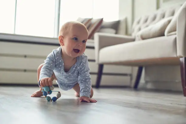 Photo of little baby boy crawling on floor at home