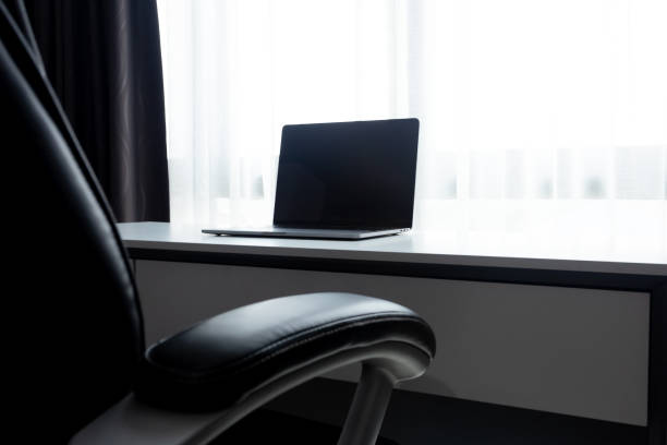 istock Desk Workplace with laptop  on white table and black chair at home office 1050183550