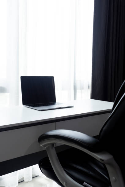 istock Desk Workplace with laptop  on white table and black chair at home office 1050183562