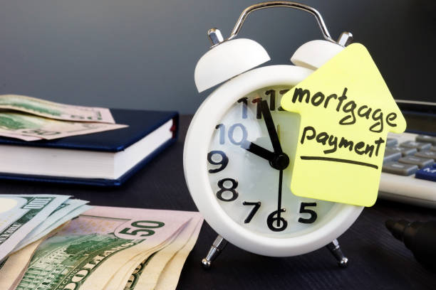 istock Mortgage payment. Alarm clock and money on a desk. 1050184208
