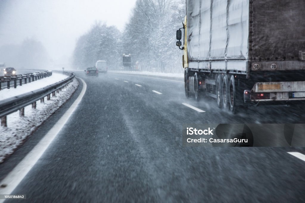 Truck Driving on Wet and Slippery Highway in Winter Truck Driving on Wet and Slippery Highway in Winter. Snow Stock Photo