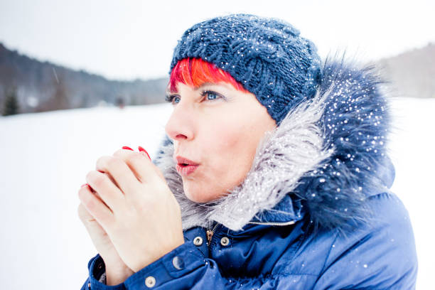 Mid Adult Woman Warming Her Hands Outdoors on Cold Winter Day.