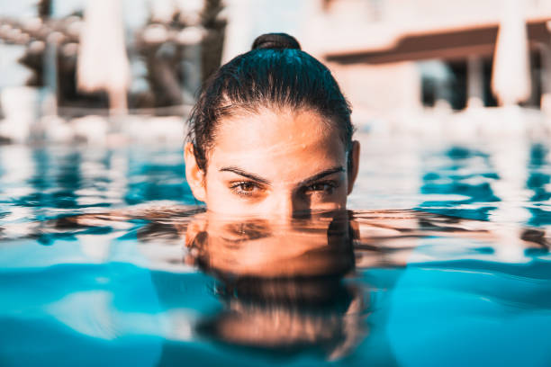 giovane donna che nuota in piscina - cheerful swimming pool happiness resort swimming pool foto e immagini stock