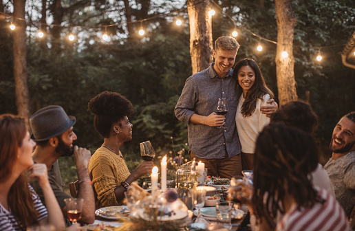 Multi ethnic group of friends have dinner party on porch, everyone enjoy in food, drinking and smiling