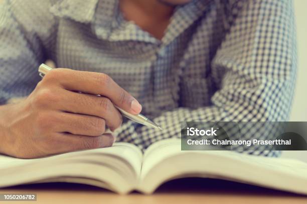 Close Up Student Man Hand Holding Pen For Guideline Reading On Text Book At Campus Library For Examination Education Concept Stock Photo - Download Image Now