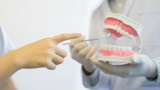 close up dentist hand use mirror explorer at teeth model denture for showing part of component inside mouth and diagnose symptom and share or give information about dental health to patient at clinic ,medical concept cerrar explorador de espejo de dentista mano uso en prótesis de dientes modelo para mostrar parte del componente dentro de la boca y diagnosticar síntomas y compartir o dar información sobre salud dental al paciente en la clínica, concepto médico