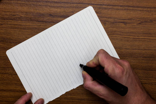 istock Business concept Empty template copy space isolated Posters coupons promotional material Man hand holding marker notebook paper expressing ideas wooden background 1050207972