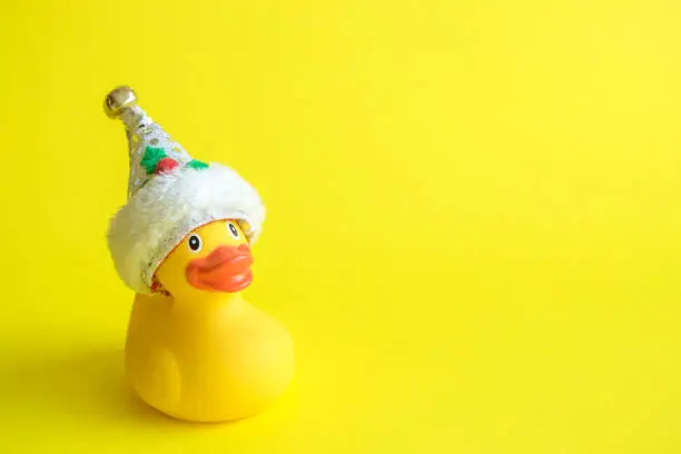 Rubber duck with Santa hat on yellow background minimal creative concept. Space for copy.