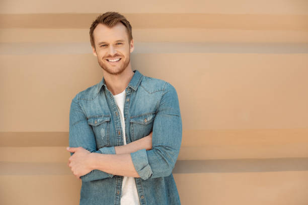 istock attractive young man looking at camera in front of wall 1050239084
