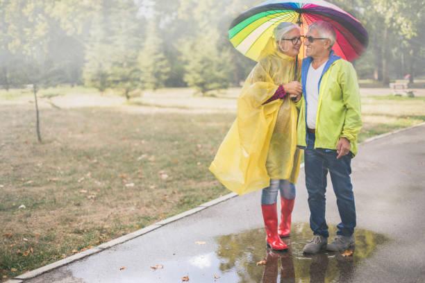 couple with a rainbow umbrella - umbrella senior adult couple autumn imagens e fotografias de stock