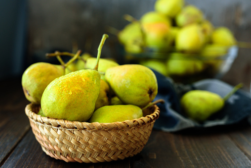 Fresh garden pears in basket on dark wooden table