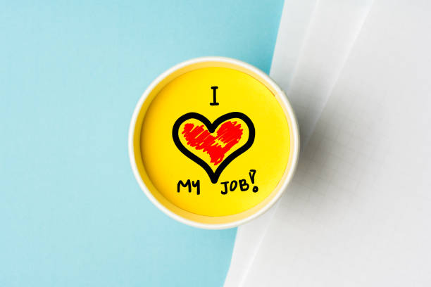 I love my job concept. Paper cup wint yellow top and blue background desk with notes. stock photo